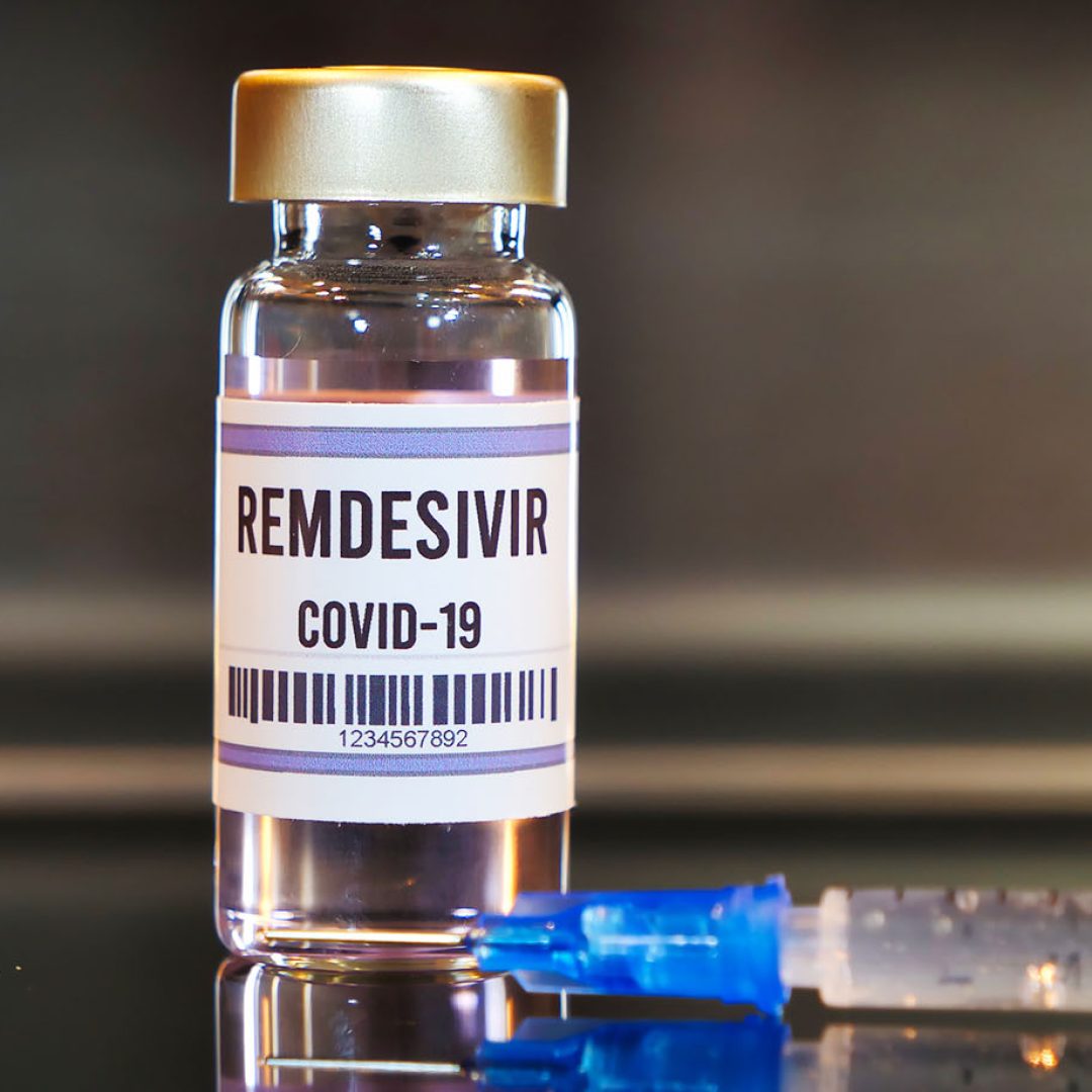 Remdesivir drug and syringe on black table with reflections and stainless background.